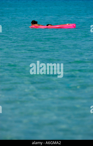 Junge Frau, die allein auf rosa Luftmatratze Perhentian Kecil Malaysia schwimmen Stockfoto