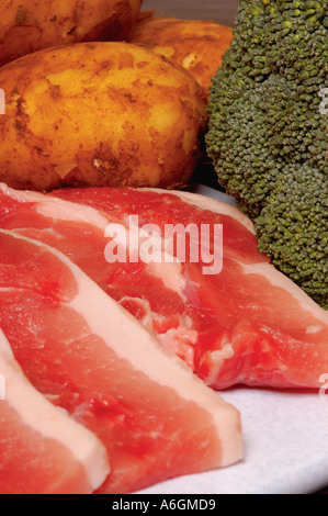 Rohe Schweinekoteletts mit neuen Kartoffeln und Brokkoli-Gemüse zum Abendessen Stockfoto