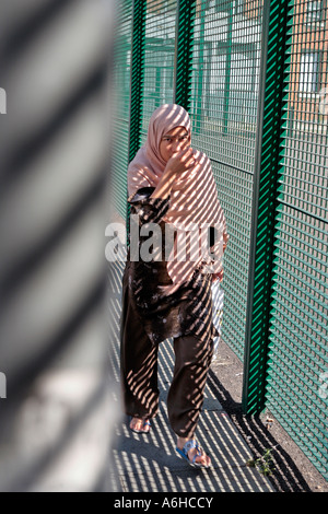 Eine asiatische Mädchen geht vorbei an einem Zaun in East London Stockfoto