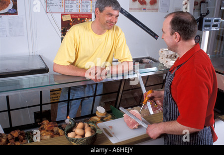 Mann im Metzger Shop kaufen Fleisch mit netten Plausch mit Verkäuferin Stockfoto