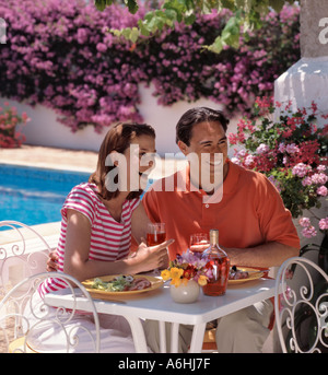 junges Paar Essen Villa Pool unter Reben und Blumen Stockfoto