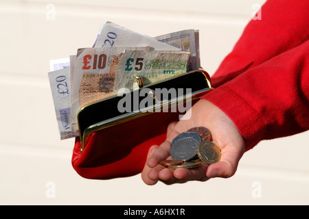 Kind eine rote Geldbörse mit Taschengeld Bargeld in der Hand hält Stockfoto