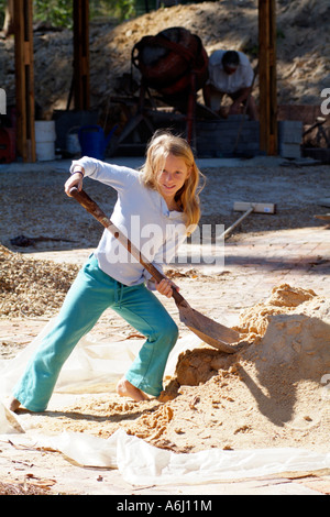 Kleines Mädchen mit einem Spaten Graben in einem Haufen von sand Stockfoto