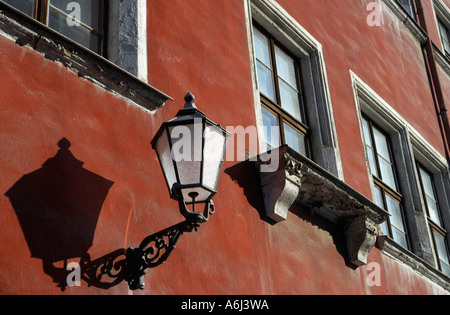 Eine geschmiedete historische Straße Lampe ist auf der Vorderseite eines alten Hauses befestigt. Stockfoto