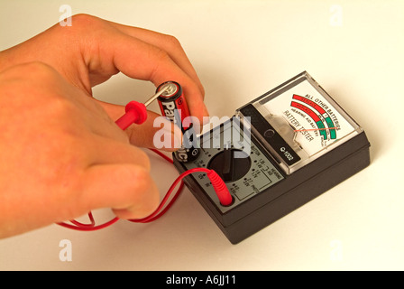 Testen einer AA-Batterie mit einem alten analogen Batterieprüfgerät Stockfoto