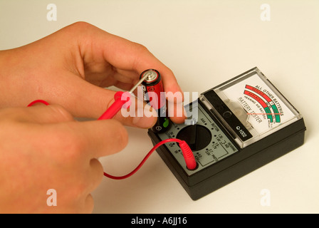 Testen einer AA-Batterie mit einem alten analogen Batterieprüfgerät Stockfoto