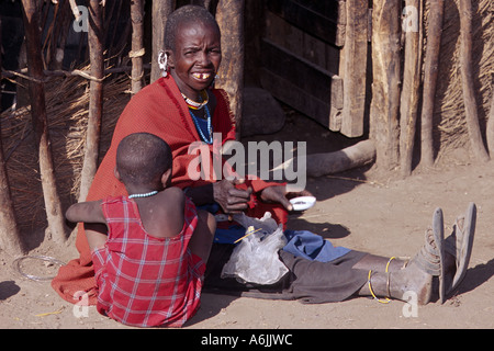 Massai Frau sitzt auf dem Boden mit einem Kind vor Hütte, Tansania Stockfoto