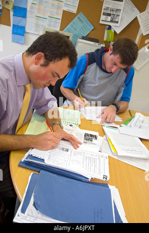 Lehrer markieren Papiere in der Schule. Beurteilung und Bewertung der schulischen Prüfungsarbeit von Schülern im Personalraum der Schuleinrichtung Stockfoto