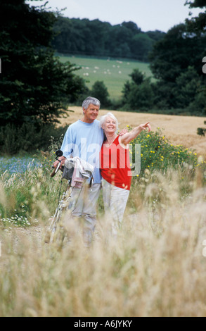 Älteres Paar mit Tandem stehen in Sussex Landschaft unter Hinweis auf Anzeigen Stockfoto