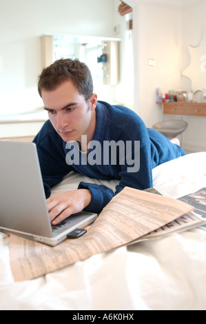 Junge britische Betriebswirt, arbeiten von zu Hause Schlafzimmer auf Laptop suchen Job London UK Stockfoto