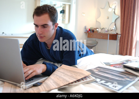 Junge britische Betriebswirt arbeitet vom Hotelzimmer auf Laptop suchen Job London UK Stockfoto