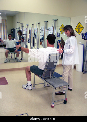 Mann im Spiegel während Krafttraining in einer Physiotherapie-Klinik mit einem Therapeuten suchen auf suchen Stockfoto