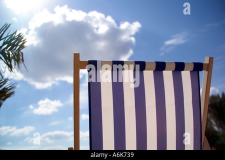 Liegestuhl und Palme unter dem blauen Himmel Stockfoto