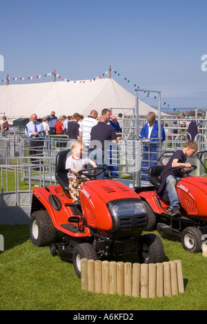 dh County Show KIRKWALL ORKNEY Kinder ausprobieren Rasenflite Rasenmäher Maschinen auf Show Boden Display Kinder Landmaschinen Kind spielen schottland Stockfoto