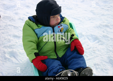 Zwei Jahre sitzt alt tragen Winterkleidung in einem Schlitten im Schnee Stockfoto