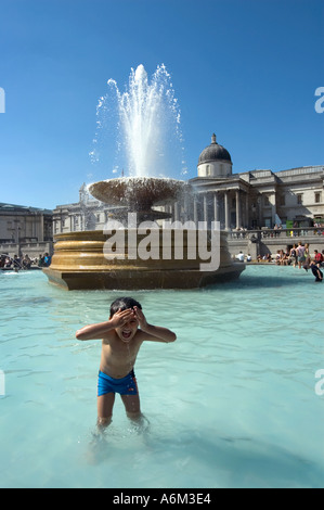 Junges Kind Abkühlung im Brunnen während der Hitzewelle am Trafalgar Square in Central London Stockfoto