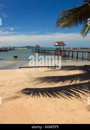 Strand mit Palmen Blätter und Schatten auf dem Sand, Bootssteg mit Jadet Pier sichtbar hinter, Ban Phe, Rayong, Provinz Rayong, Thailand Stockfoto