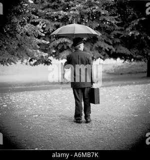 Mann mit Regenschirm und Aktenkoffer im Regen Stockfoto