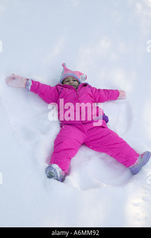 Latina Mädchen spielt, macht Schneeengel Schnee Upstate New York Stockfoto