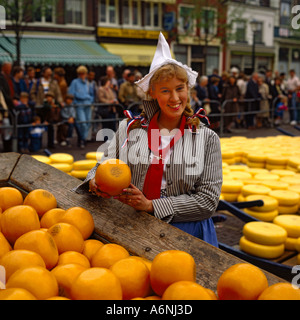 Lächelnd Holländerin in traditioneller Tracht halten Runde Edamerkäse auf traditionelle Käsemarkt in Alkmaar Holland Stockfoto