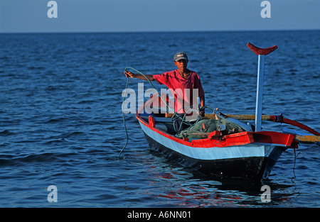 Young-Balinesen Fischer in seinem Prahu Pemuteran ein Fischerdorf auf Bali s N Küste an Land zu kommen Stockfoto