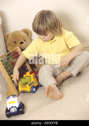 Kleiner Junge spielt mit Spielzeug aus Plastik Einsatzfahrzeuge Stockfoto