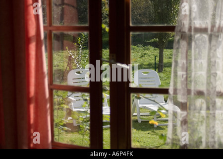 Blick in den Garten durch die leicht geöffnete Fenster mit traditionellen Holz Rahmen Frankreich Stockfoto