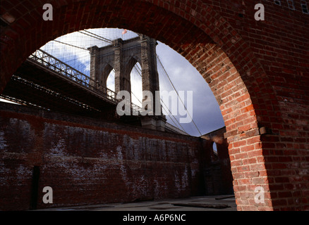 Brooklyn Bridge gesehen durch die alten Lager Bögen bei Sonnenuntergang in Brooklyn New York Amerika Stockfoto