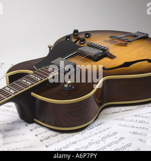 Eine Hohlkörper-jazz-Gitarre sitzt oben auf einige Noten Stockfoto