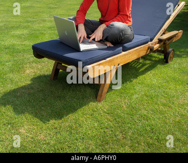 EINE PERSON SITZT IM GARTEN AUF EINEM LAPTOP Stockfoto