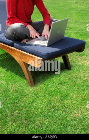 EINE PERSON SITZT IM GARTEN AUF EINEM LAPTOP Stockfoto