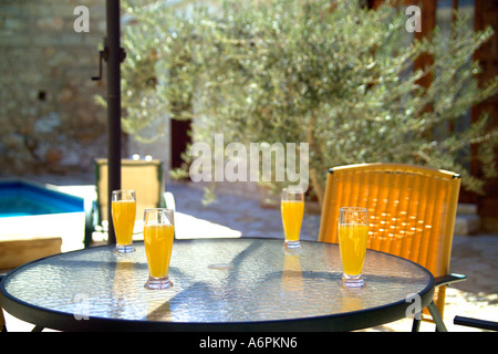 TABELLE MIT ORANGENSAFT ALFRESCO IN DER ABENDSONNE MIT POOL IM HINTERGRUND Stockfoto