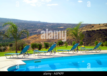 Panoramablick auf Sonnenliegen und Swimmingpool in Zypern über Berge, Hügel Stockfoto