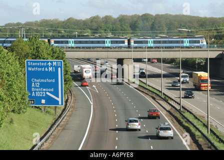 Verkehrsinfrastruktur Eisenbahnbrücke & schneller Personenzug Überquerung über dem Straßenverkehr an der Kreuzung 28 M25 Autobahn Brentwood Essex England UK Stockfoto