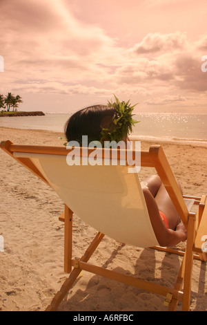 Frau liegend in Strand Stuhl tragen Haku Lei Sonnenuntergang auf sandigen Strand Oahu Hawaii Stockfoto