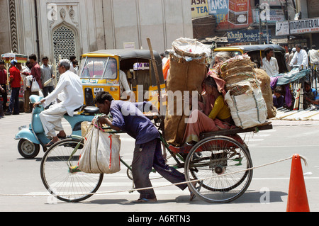 Cycle rickshaw Treiber transportiert Güter für die alte Dame in der Altstadt von Hyderabad, Andhra Pradesh, Indien Stockfoto