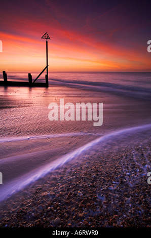 Wellen-Welle nach oben und unten am Strand unter einem brennenden Himmel im Morgengrauen in Hayling Island, Hampshire Stockfoto