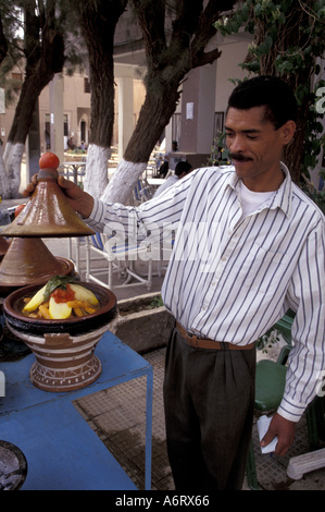 Afrika, Marokko, El Kelaa des Mgouna Kellner hebt den Deckel ab Traditionsgericht der Tajine (Fleisch- und Gemüseeintopf) Stockfoto