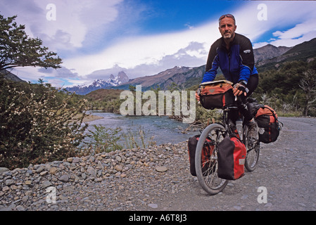 Männliche Radfahrer mit Bart und Sonnenbrille im argentinischen Patagonien mit Fitzroy Berge im Hintergrund auf holprigen Straße neben r Stockfoto