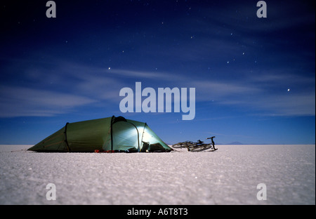 Zelt und Fahrrad auf Salz Wohnung des Salar de Uyuni in Bolivien auf 3600 Mteres Höhe um Mitternacht mit Sternspuren im tiefblauen nig Stockfoto