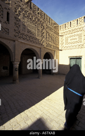 Afrika, Tunesien Tozeur Oase. Verschleierte Frau in der Altstadt; Ziegel Stein Häusern und gepflasterten Straße. Stockfoto