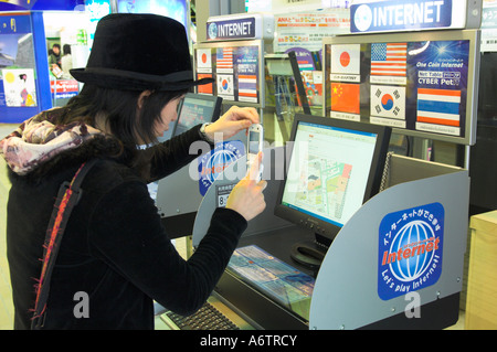 Japan nördlichen Honshu Miyagi Ken Sendai Train Station weiblicher Jugendlicher ein Foto von einem Computer-Bildschirm mit ihrem Handy im Gespräch Stockfoto