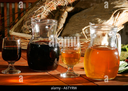 2 Karaffen und Gläser mit roten und weißen Wein, italienischer Wein des Hauses vor einem Korb mit Salami Wurst und Schinken Stockfoto