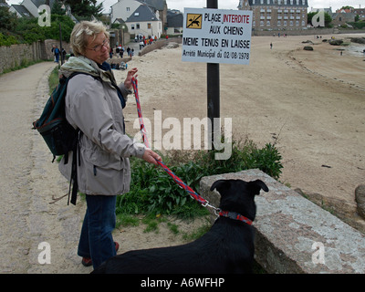 Herr PR Spaziergang mit dem Hund an einem Verbotszeichen für Hunde am Strand Stockfoto