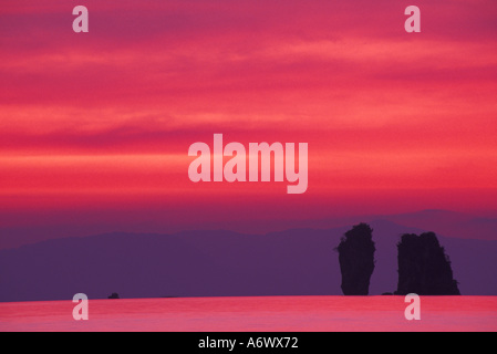 Asien, Thailand, Phang Nga Bucht. Rosa Himmel spiegelt sich im Meer mit gezackten Karst (Kalkstein) Inseln Stockfoto