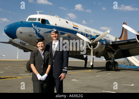 Flugbegleiter in traditionellen 50er Jahre Uniformen stehen neben einer alten South African Airways DC-4. Stockfoto