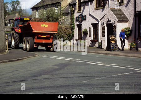 FOOLOW Dorf DERBYSHIRE UK Mai ein Traktor fährt durch das Dorf ziehen eines Anhängers mit Gülle geladen Stockfoto