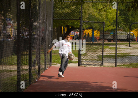 ILLINOIS-Chicago Junge kick Fußball über Tennis Court Park in Pilsen Nachbarschaft Stockfoto