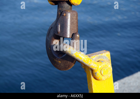 Detail von einem gelben industrielle Haken für schwere Gewichte über einen blauen Meerwasser. Stockfoto