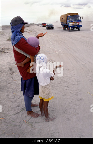 Phiippino Frau mit ihrem Baby und Kind betteln neben der trostlosen staubigen Straße nach Manila in Philippinen Stockfoto